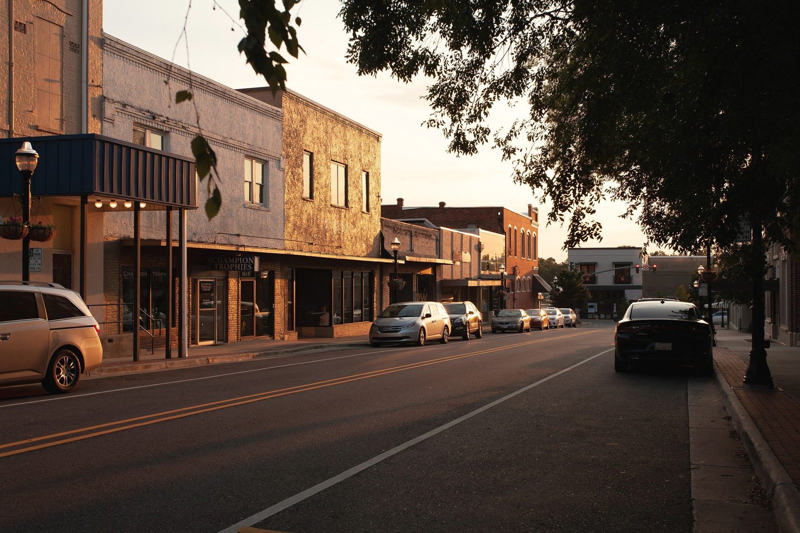 Low sun along West Mississippi Avenue in Ruston with brick storefronts and parked cars